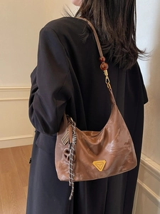 Brown half-moon crossbody bag with marble texture and golden triangle plaque on black blazer