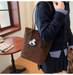 Brown suede tote bag detail with a cute horse charm and slim shoulder strap