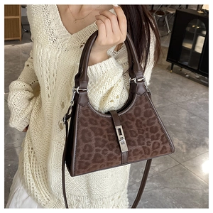 Detail of leopard print bucket bag with metal buckle and brown leather handle on a beige sweater