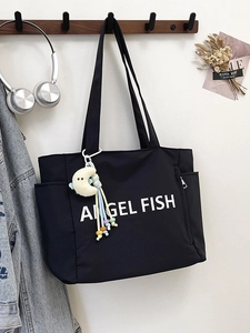 Sac fourre-tout noir en nylon avec lettrage blanc et breloque à pompon sur mur blanc