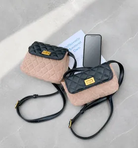 Detail of color-block quilted crossbody bag with golden metal turn-lock on asphalt street
