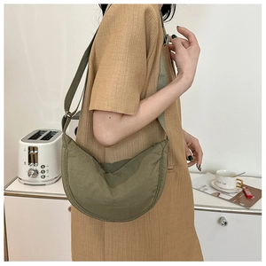 Olive green nylon crescent bag shown with adjustable shoulder strap on a male model