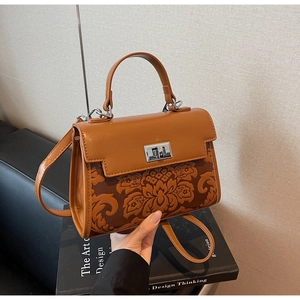 Detail of vintage brown lady handbag featuring floral embossed texture and silver twist lock