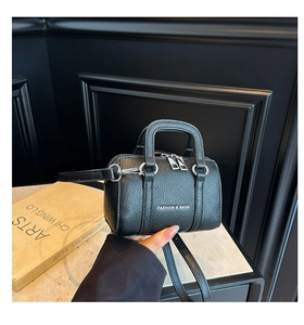 Détail du mini sac Boston noir à grain de litchi avec logo argenté et texture cuir