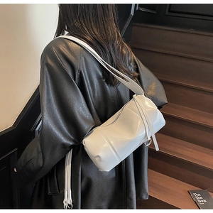 Chic light gray cylinder crossbody bag shown on model with sleek patent leather finish