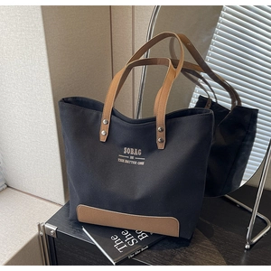 Detail of canvas tote bag featuring brown leather straps and SOBAG logo print