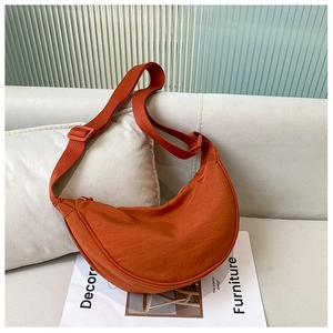 Detailed texture of burnt orange nylon crescent bag on light fabric sofa background