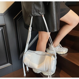 Detail of adjustable strap and silver zipper on white cylindrical crossbody bag