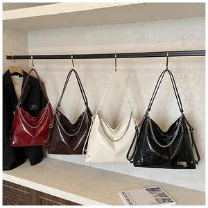 Detail of four colorful glossy oil wax leather tote bags with silver chain ornaments