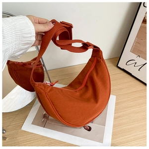 Close-up of burnt orange nylon crescent bag showing water-resistant texture and zipper
