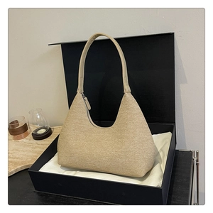 Detail of beige woven hobo bag with sleek leather handle inside a stylish gift box