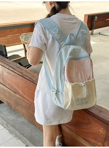 Detail of a light blue and pink patchwork nylon backpack with drawstring front pocket