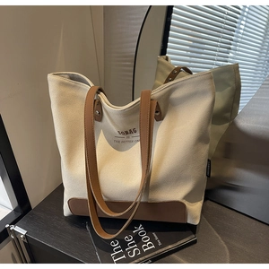 Detail of canvas tote bag with brown leather straps and reinforced metal rivets