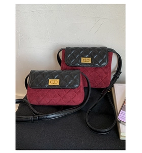 Detail of burgundy suede and black leather patchwork bag with golden twist lock