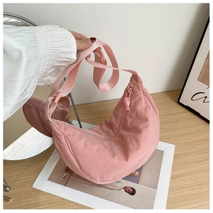 Pink nylon crescent hobo bag with adjustable strap on a minimalist wooden table
