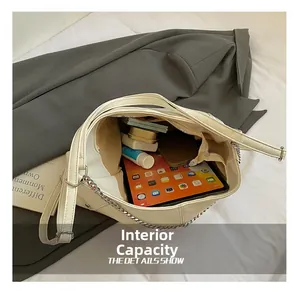 Spacious interior of beige hobo bag holding an iPad, phone, and cosmetics with silver chain