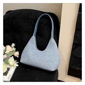 Close-up of light blue textured tweed hobo bag on a black corduroy chair with roses