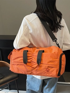 Large orange travel duffel bag with stylish pleats and detachable shoulder strap