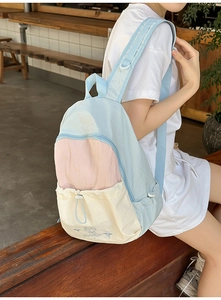 Outdoor view of multi-color pastel backpack with embroidery on wood background