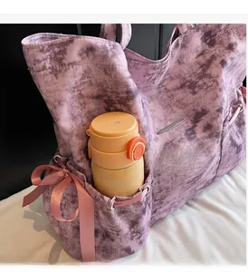 Détail du sac cabas tie-dye violet avec poche latérale, nœud rose et gourde d'eau