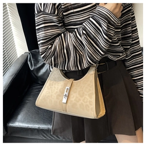 Detail of beige leopard print hobo bag with silver piston lock on model shoulder