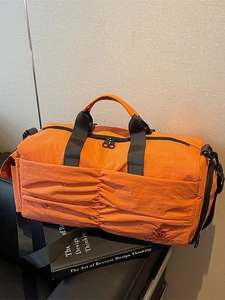 Orange high-capacity waterproof travel bag with pleated front pocket and shoulder strap