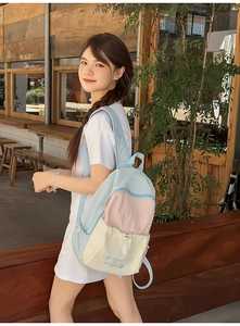 Detail of Korean style backpack showing light blue and pink contrast panels and embroidery