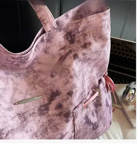 Détail du sac cabas en toile tie-dye rose avec cordon de serrage et boucle en métal