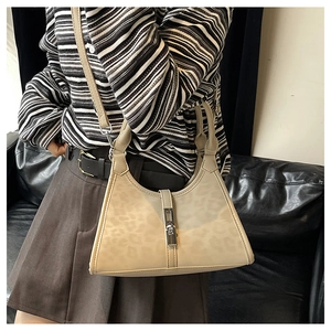 Detail of beige leopard print bucket bag featuring a silver piston buckle and leather strap