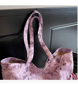 Gros plan d'un sac cabas en toile tie-dye violet avec des poignées larges sur un bureau