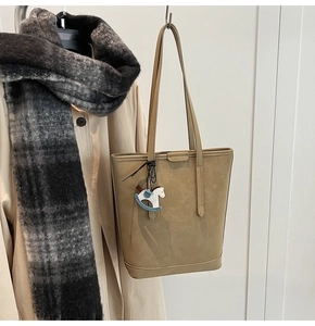 Detailed shot of khaki tote bag with matte texture and a blue rocking horse charm