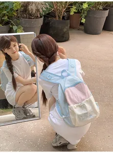 Detail of color-block backpack with Good Morning embroidery shown in a mirror reflection