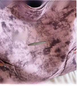 Gros plan sur la toile tie-dye violette et sa plaque métallique argentée en navette