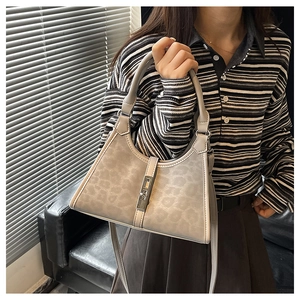 Detail view of small grey leopard print bucket bag with silver metal rotating lock and strap