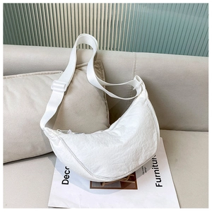 Detail of white nylon half-moon bag with adjustable strap on beige sofa background