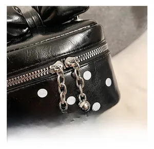 Macro shot of silver zipper with metal chain and bead charm on polka dot mini bag