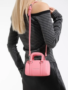 Mini sac Boston rose en cuir grainé avec bandoulière réglable porté par un mannequin