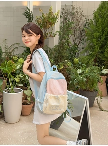 Detail of three-color pastel backpack featuring drawstring front pocket and embroidery
