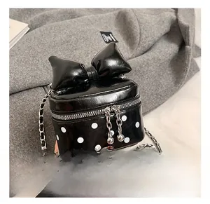 Detail of a black leather crossbody bag with oversized bow and white polka dots