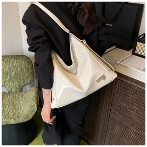 Detailed shot of cream large shoulder bag with silver chain and glossy faux leather texture