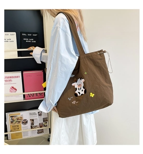 Detail einer braunen Canvas-Tasche mit süßer Kuh-Stickerei und Kordelzugverschluss