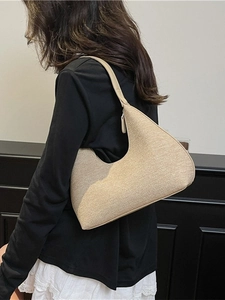 Minimalist beige woven hobo shoulder bag with leather strap shown on model's shoulder