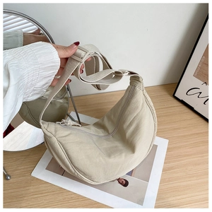 Minimalist cream crescent nylon crossbody bag with adjustable strap in home setting
