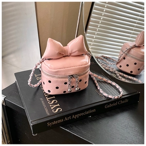 Macro view of pink polka dot mini bag with bow detail and silver chain strap
