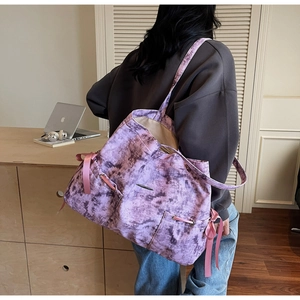 Détail du sac cabas tie-dye violet avec rubans roses dans un décor de bureau moderne