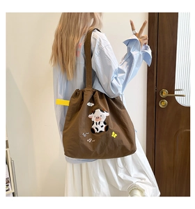 Braune Canvas-Umhängetasche mit Kuh-Stickerei, präsentiert von einem Model zu Hause