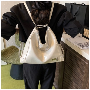 Detail of glossy cream leather backpack with silver chain strap and heart charm decoration