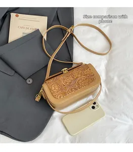 Detailed view of khaki embossed leather crossbody bag showing size compared to smartphone