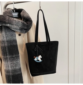 Macro detail of black matte tote bag featuring a cute blue horse pendant and long straps