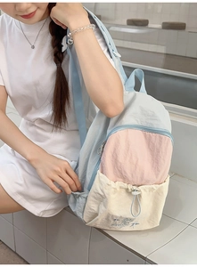 Detail of tricolor nylon backpack showing drawstring pocket and fine embroidery